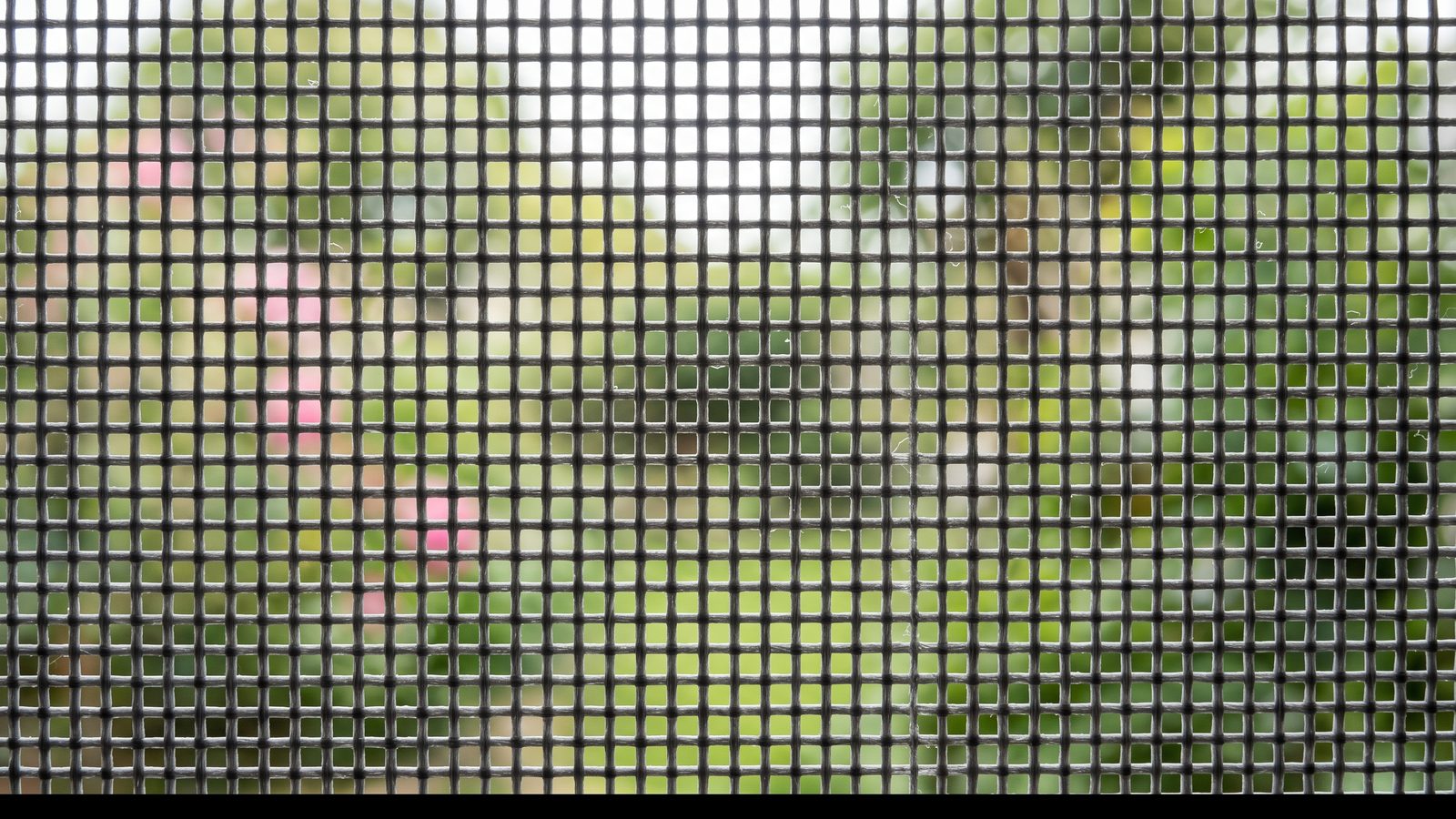 Macro view of grey sunscreen blind fabric backlit to show the open weave between the yarns