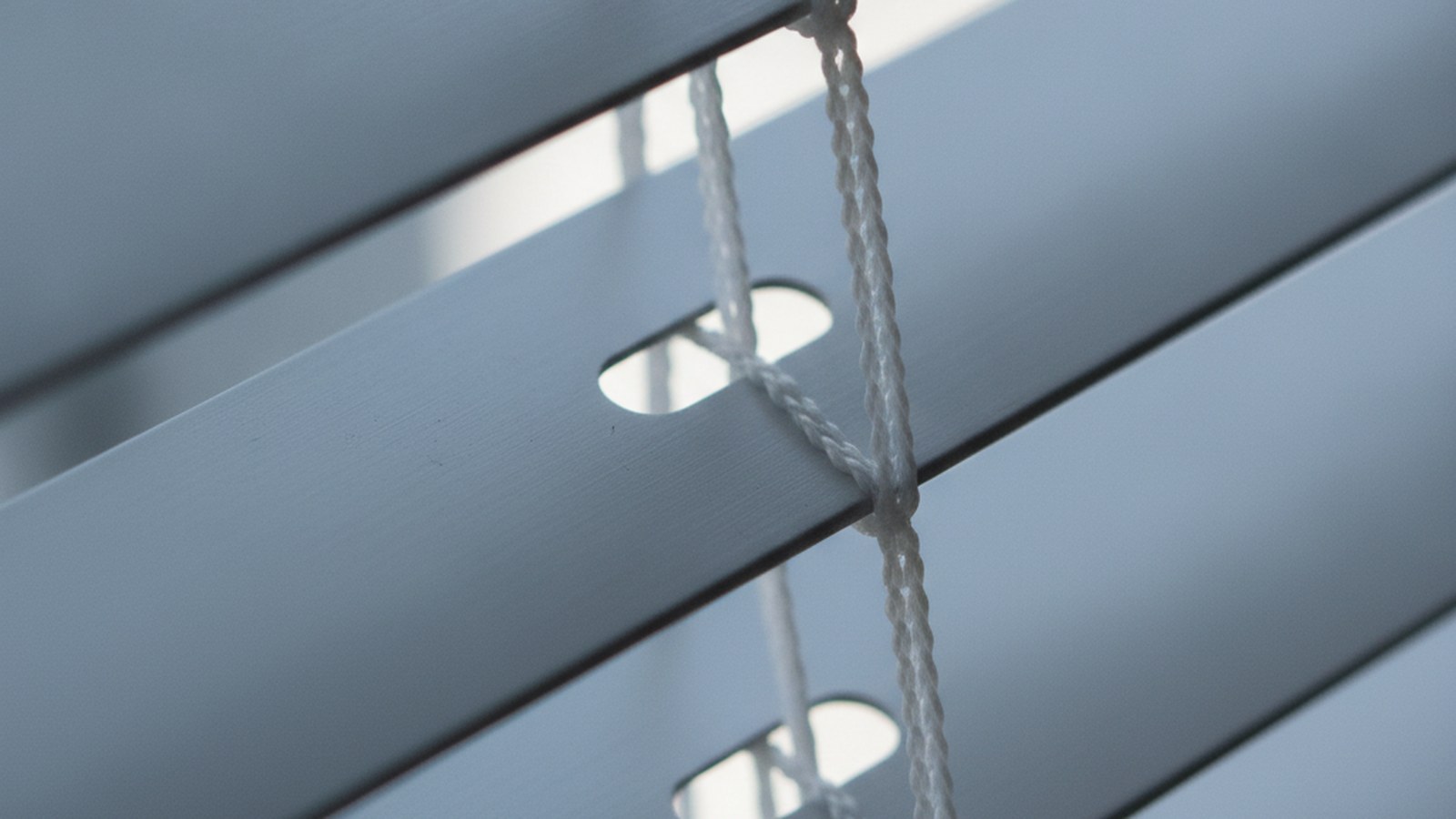 Close-up of 25mm aluminium venetian blind slats showing the ladder cord through the slat holes